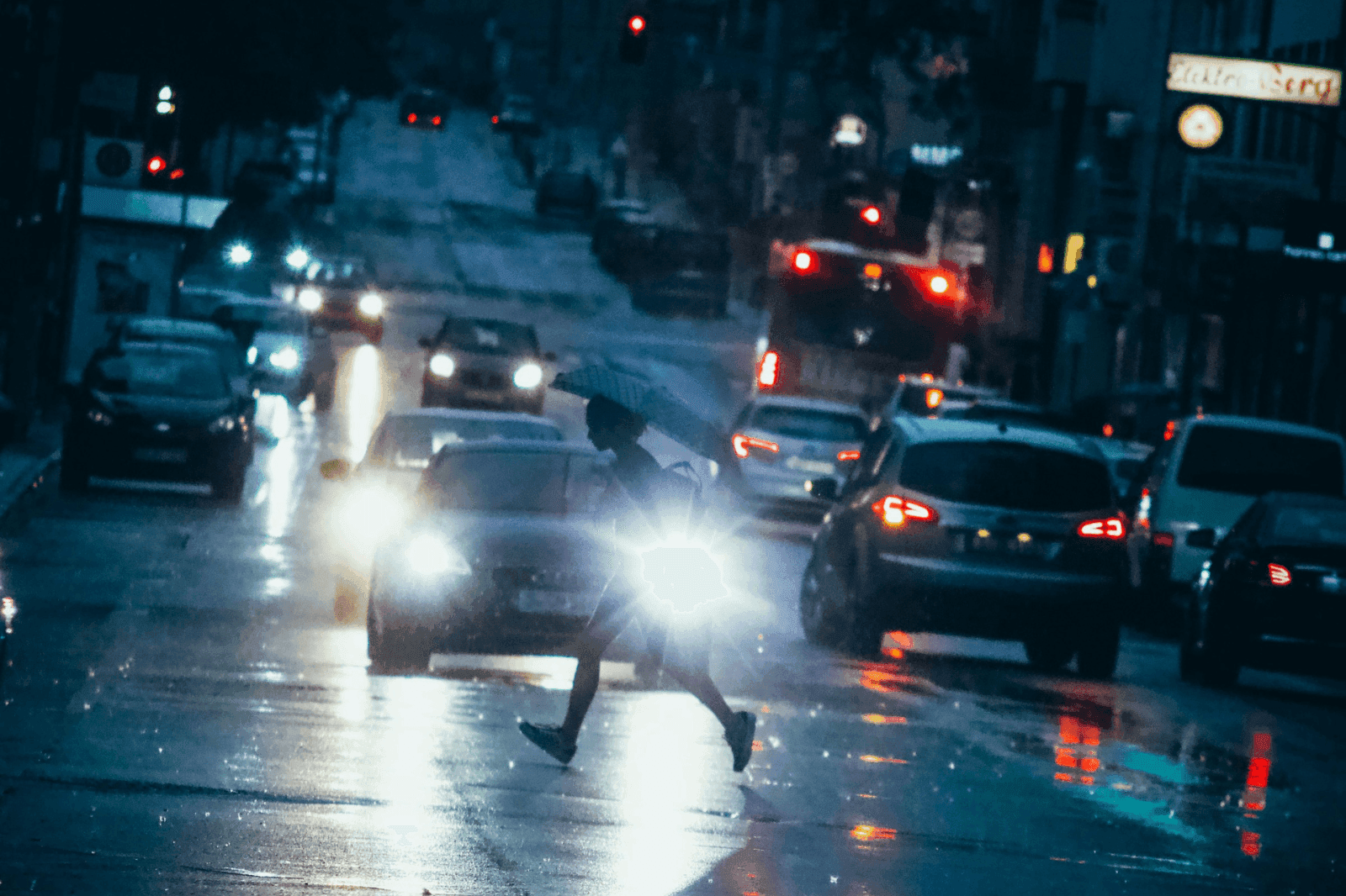 christian-lue-pedestrian-danger-unsplash A pedestrian runs across the street as cars with bright headlights near their path