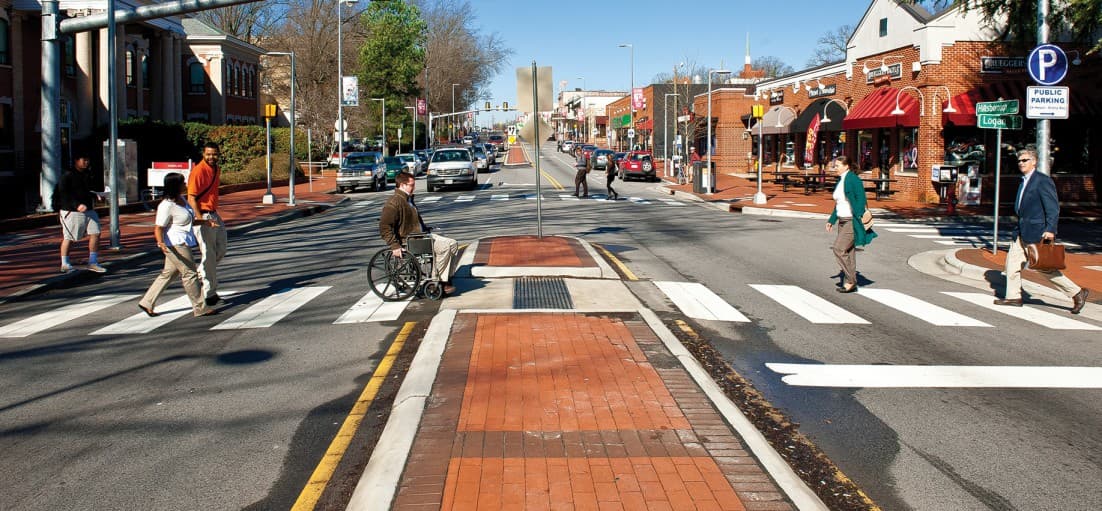 walkbike nc crosswalk Pedestrians use a marked crosswalk to cross two vehicle lanes separated by a median.