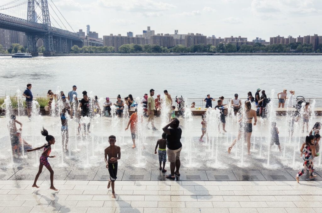 Children playing in public splash pad beside a river.
