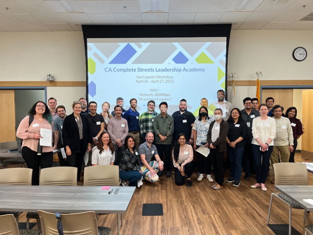 A group of people gather in front of a presentation screen in San Leandro, California.