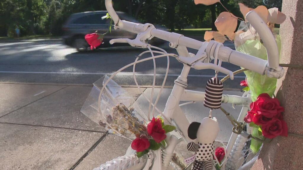 A white ghost bike with roses sits at the intersection of Grand Blvd and Magnolia Ave in St. Louis.