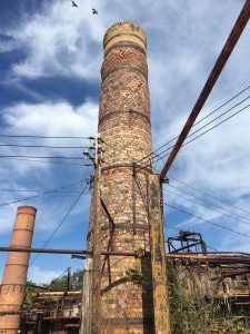 A brick chimney towers over a nearby kiln at a defunct clay plant. 