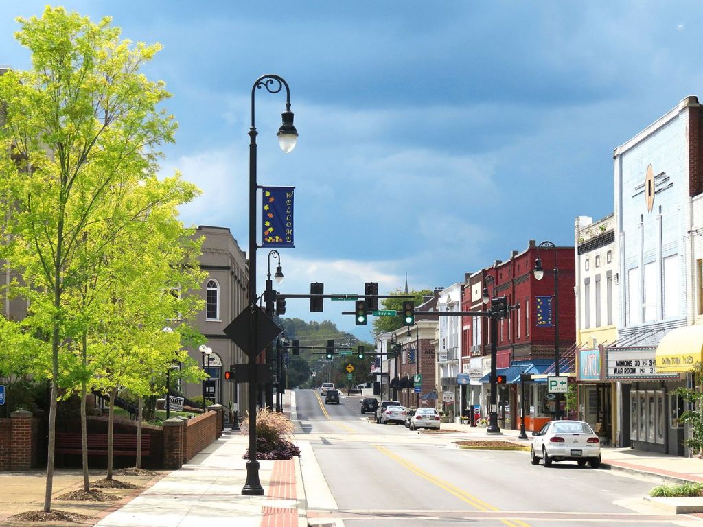a small town in eastern tennessee with a storefronts on the right and beautiful light poles providing street light for pedestrians