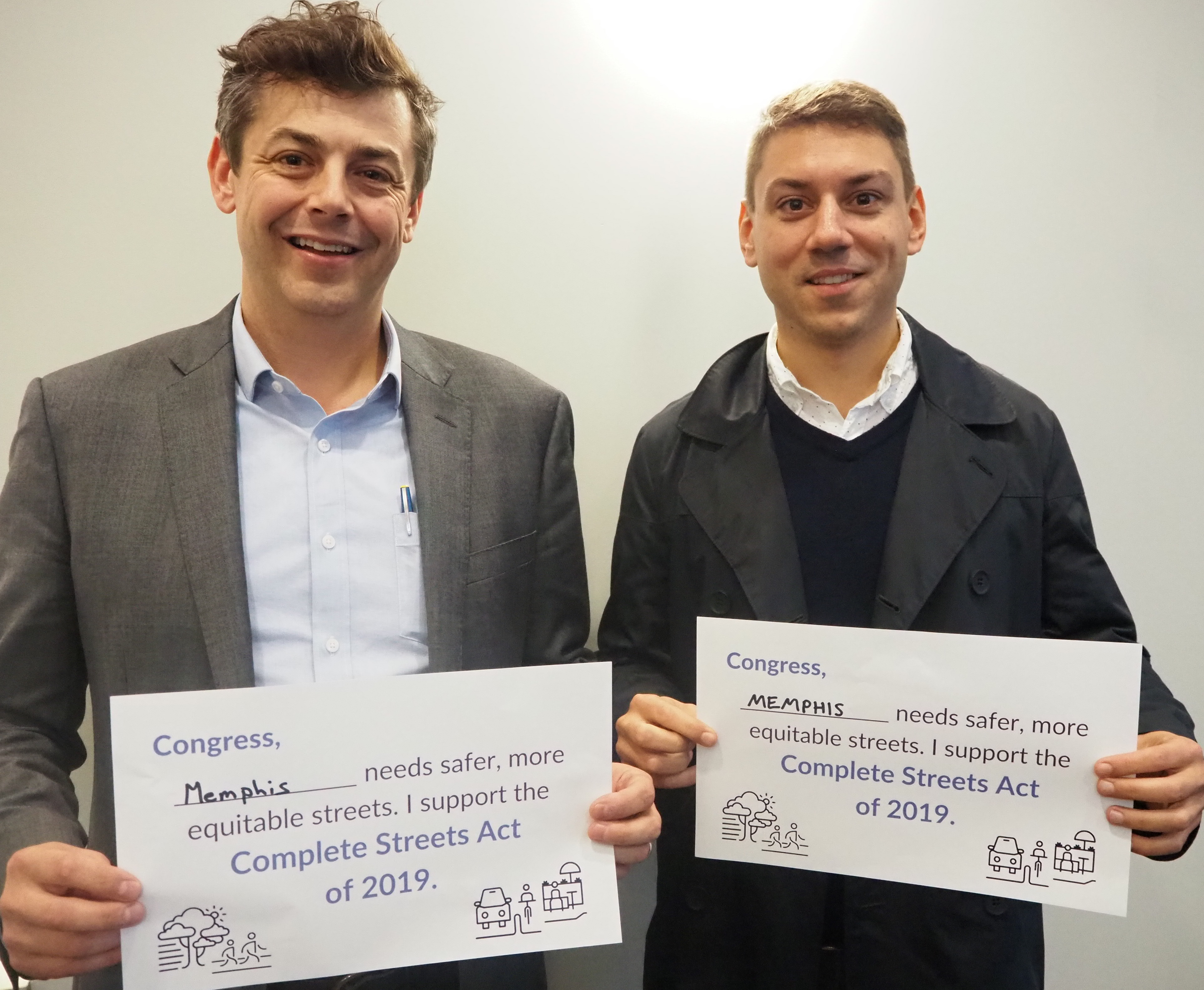 Tommy Pacello and George Abbott holding signs supporting the Complete Streets Act