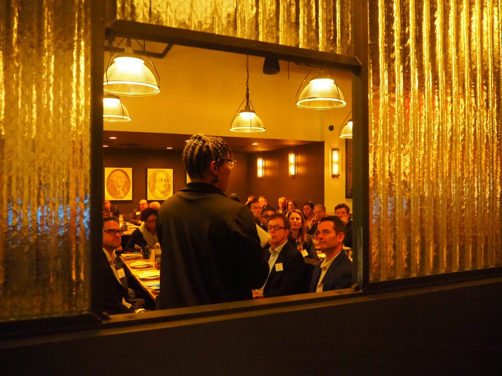 Visible through an opening in the wall, Anita Cozart delivers remarks at the 10th Annual Complete Streets dinner. 