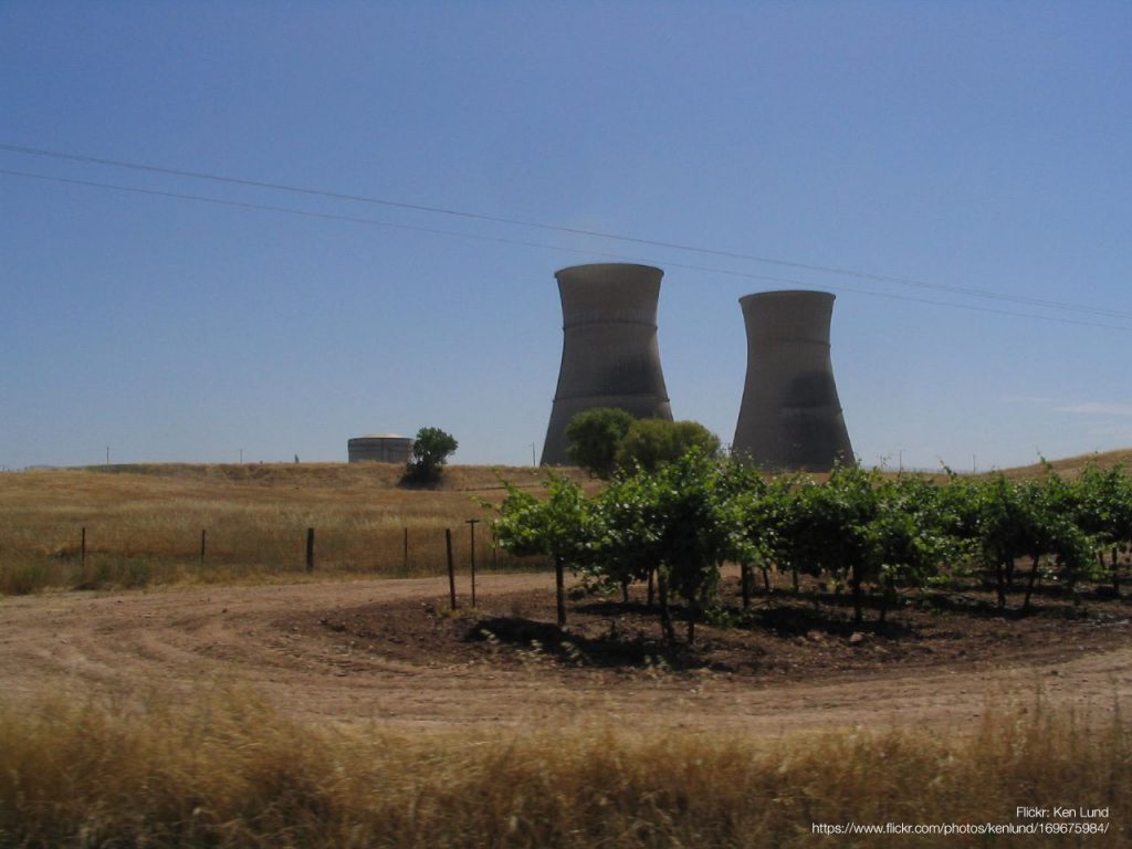 Photo of the cooling towers of a decommissioned nuclear plant rising above fields of crops