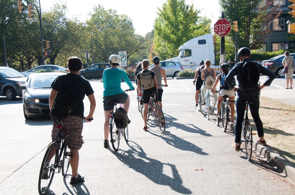 Cyclists queue at a stop sign.