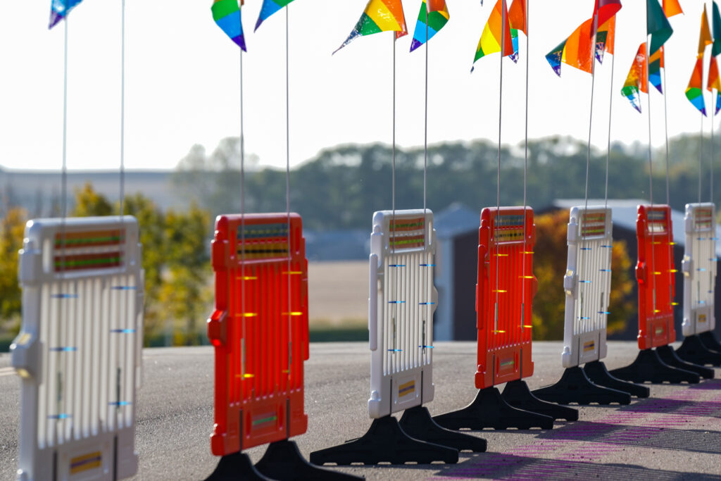 Image of series of orange and white barricades topped with rainbow flags.