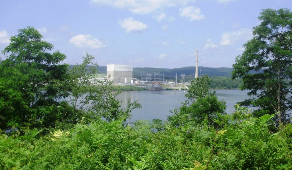 nuclear power plant on riverfront framed by foliage and trees in the foreground