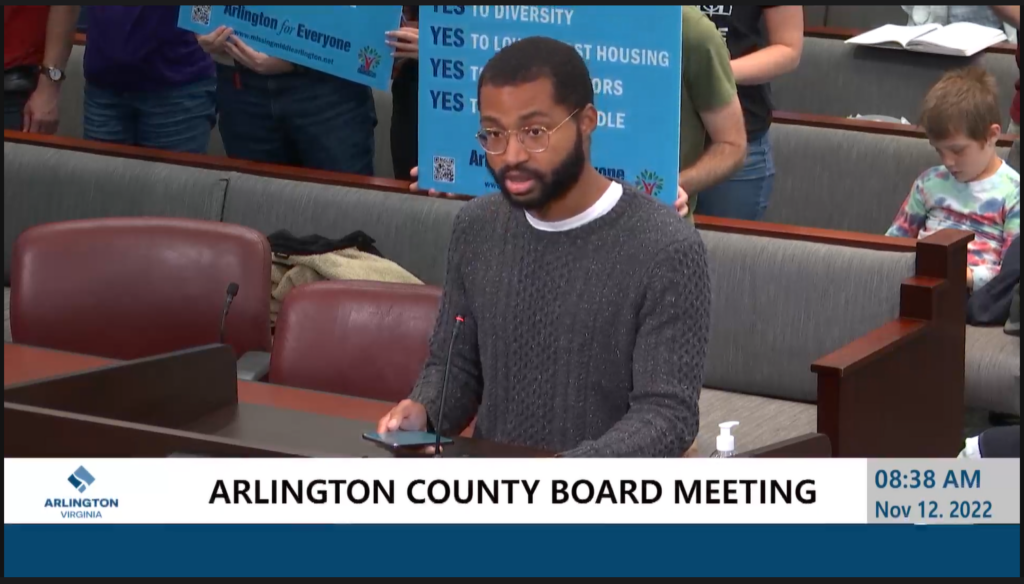 Bryan Coleman speaks at a podium, at an Arlington County Board Meeting. 