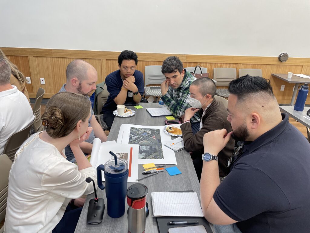 A group of people gather around a table, looking at a map. 