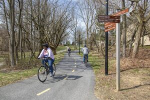 Howard County residents biking on a tree-lined trail in Columbia, Maryland