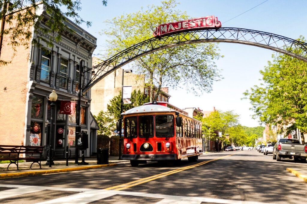 Red transit trolley with historic design passes through an arch that reads "Majestic" in Chillicothe, Ohio.