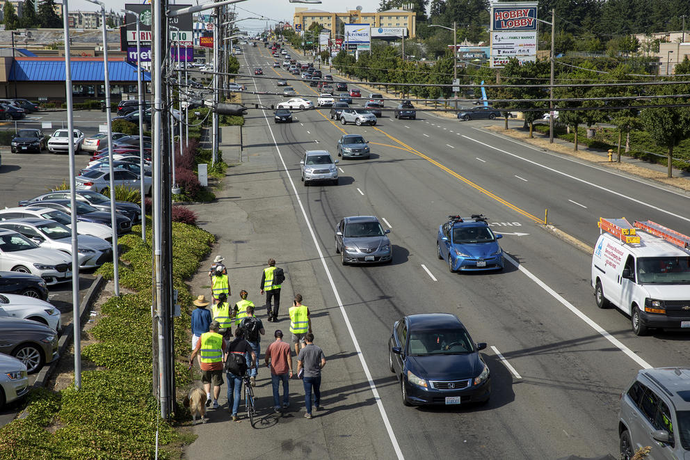 obligue angle of an arterial road with 5 lanes and a wide shoulder where people are walking