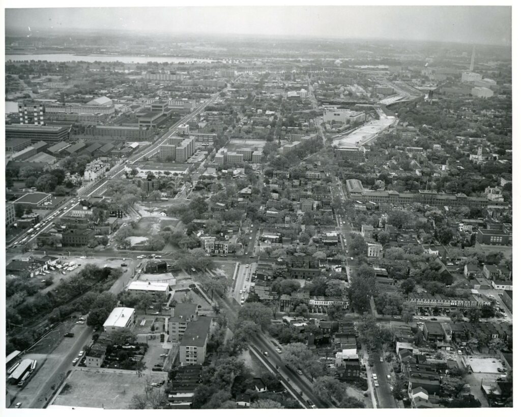 aerial oblique photo shows interstate construction tearing through DC neighborhood from above with washington monument visible in background