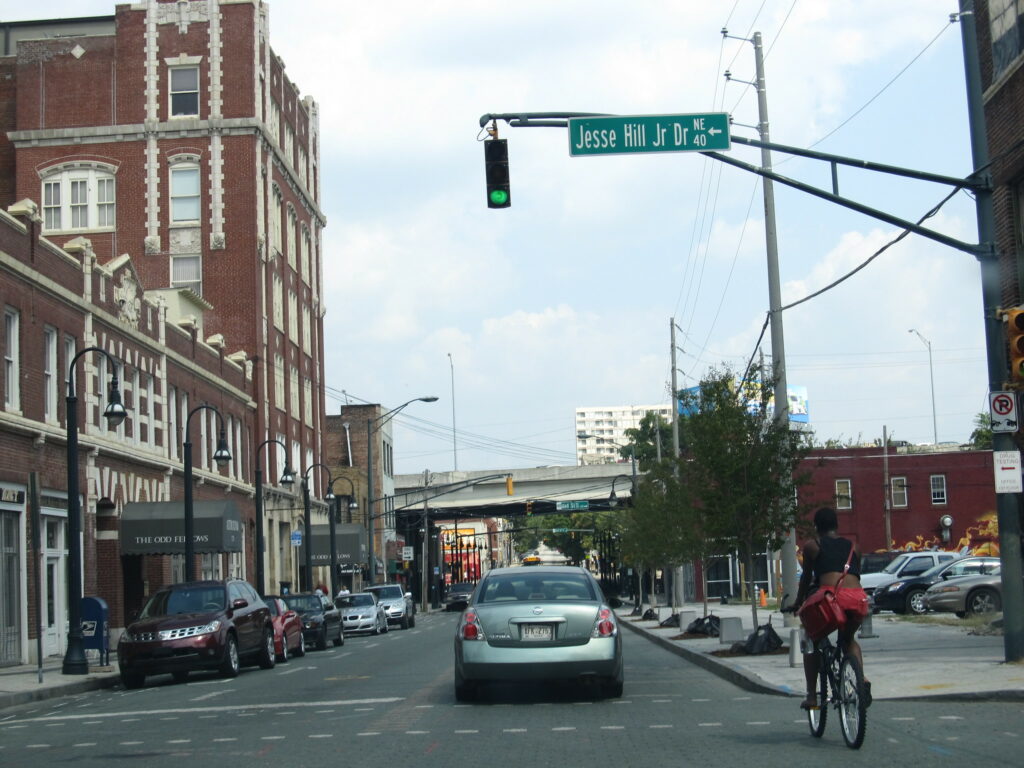 a street scene with a person biking on a city street with an interstate viaduct visible in the distance