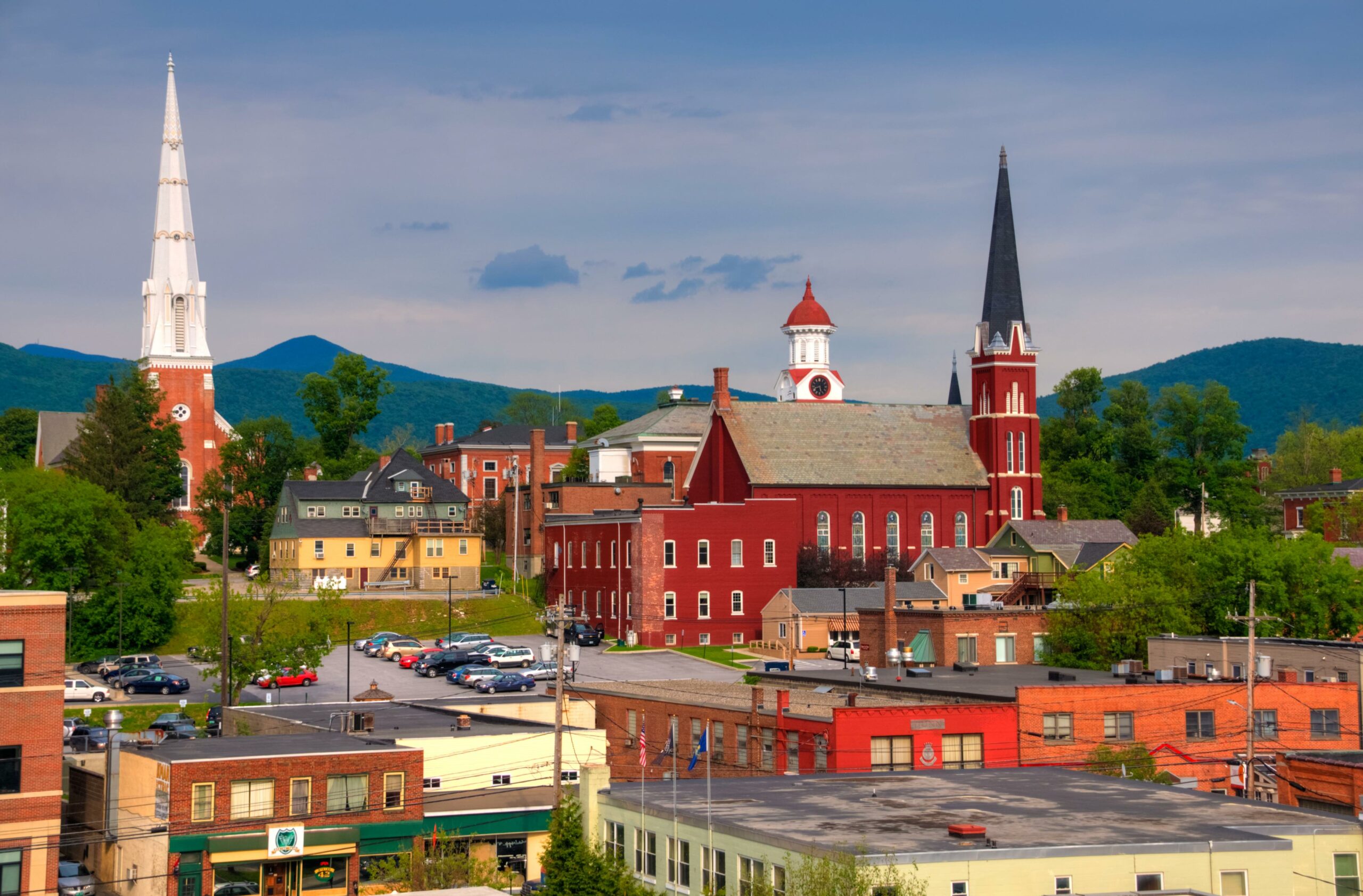 A landscape photo of Rutland, Vermont with tall, red, brick buildings and trees. 