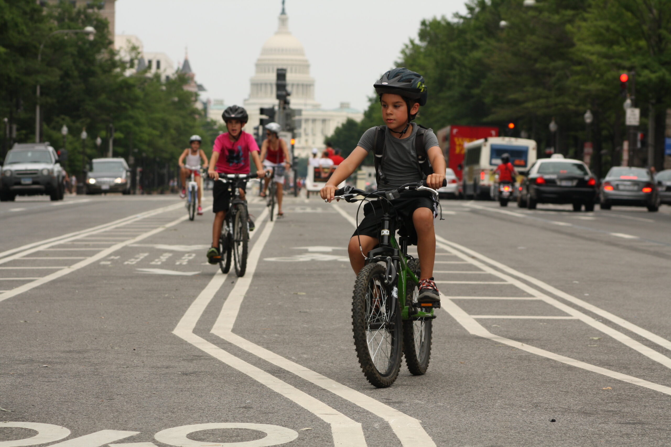 A group of children ride down a bike lane in front of the U.S. Capitol building