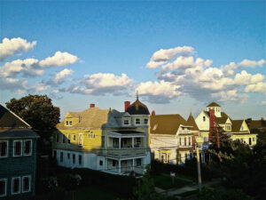 A blue sky and sun that sets on a row of houses in Somerville Massachusetts