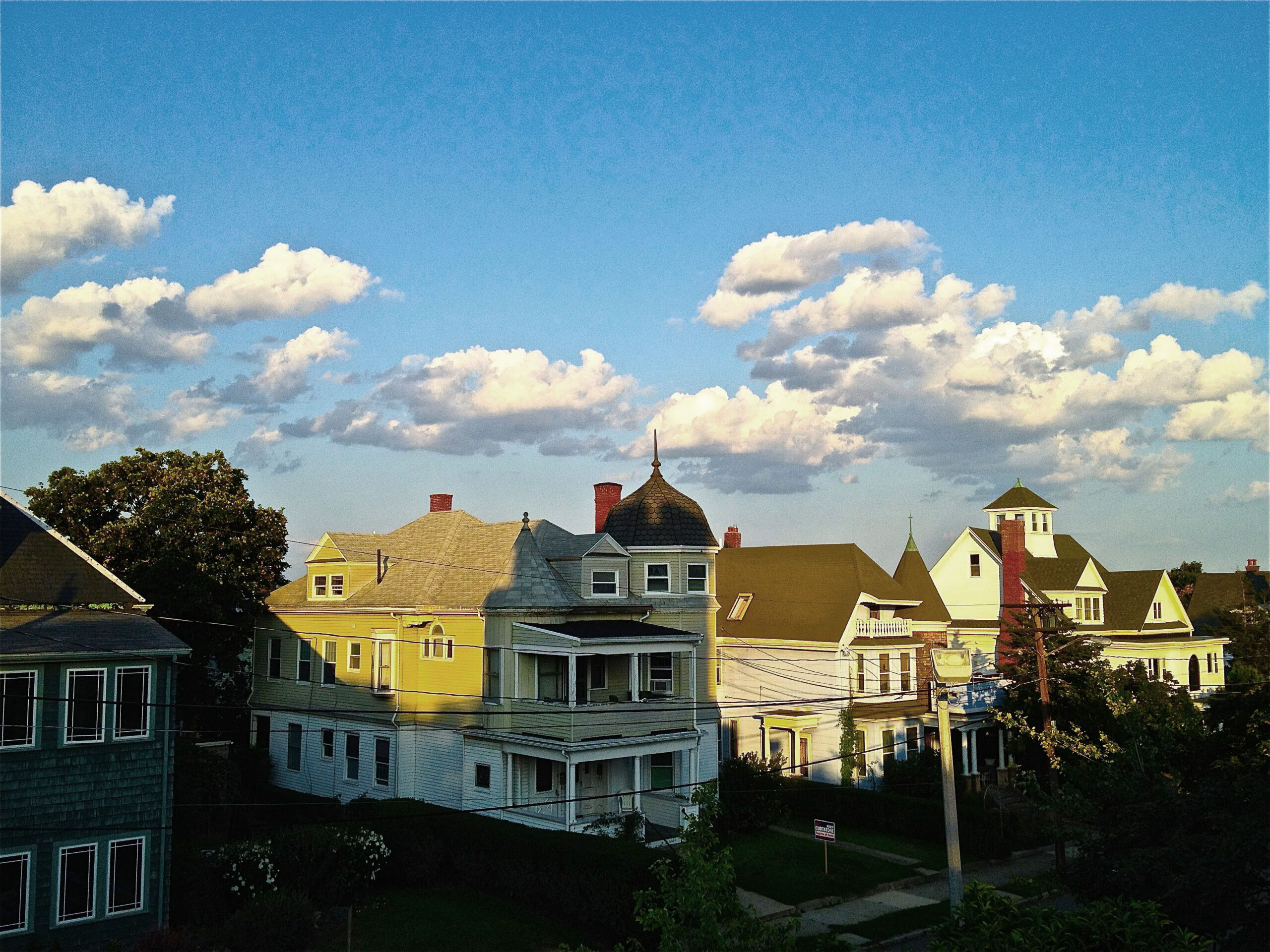 A blue sky and sun that sets on a row of houses in Somerville Massachusetts