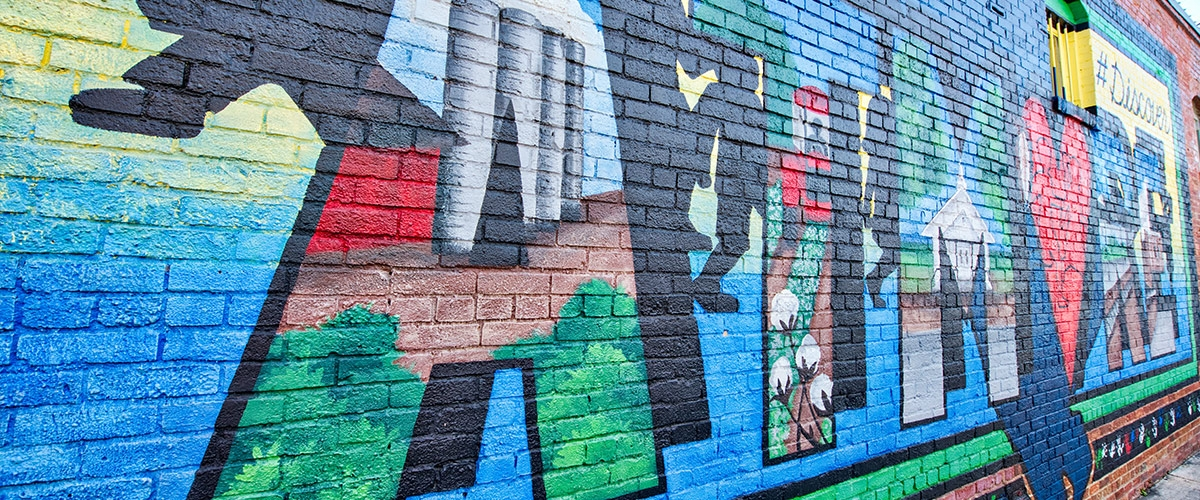 Close-up of a colorful mural in Atmore, Alabama depicting trees, people, and nature along with the town's name