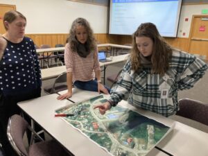 Three women gather around a table looking at a map of their city.