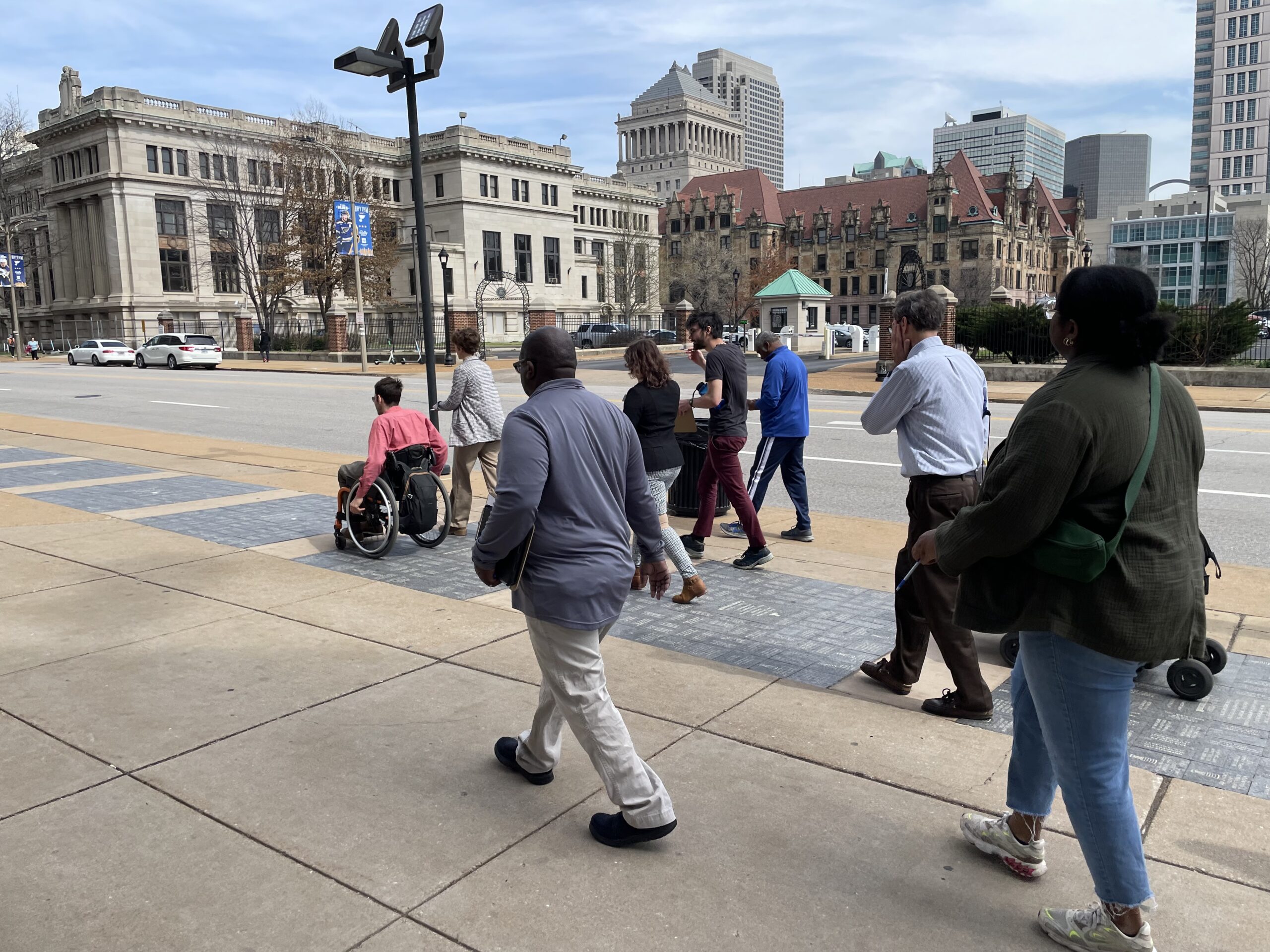 Dustin, the author of this post, rolls ahead of a group of elected officials and community members participating in a walk audit in front of City Hall in St. Louis, MO.