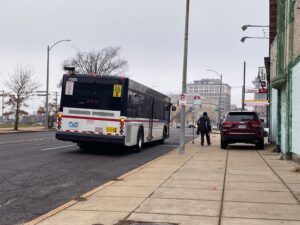 A bus stops on Grand Blvd to pick up a passenger.