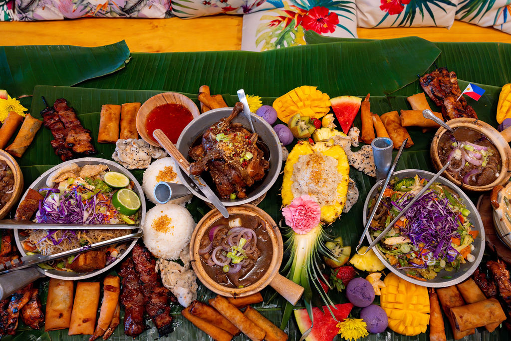 A table at the restaurant Kamayan ATL displaying a variety of Filipino dishes laid out on banana leaves in the kamayan style of communal dining, which is Tagalog for "by hand."