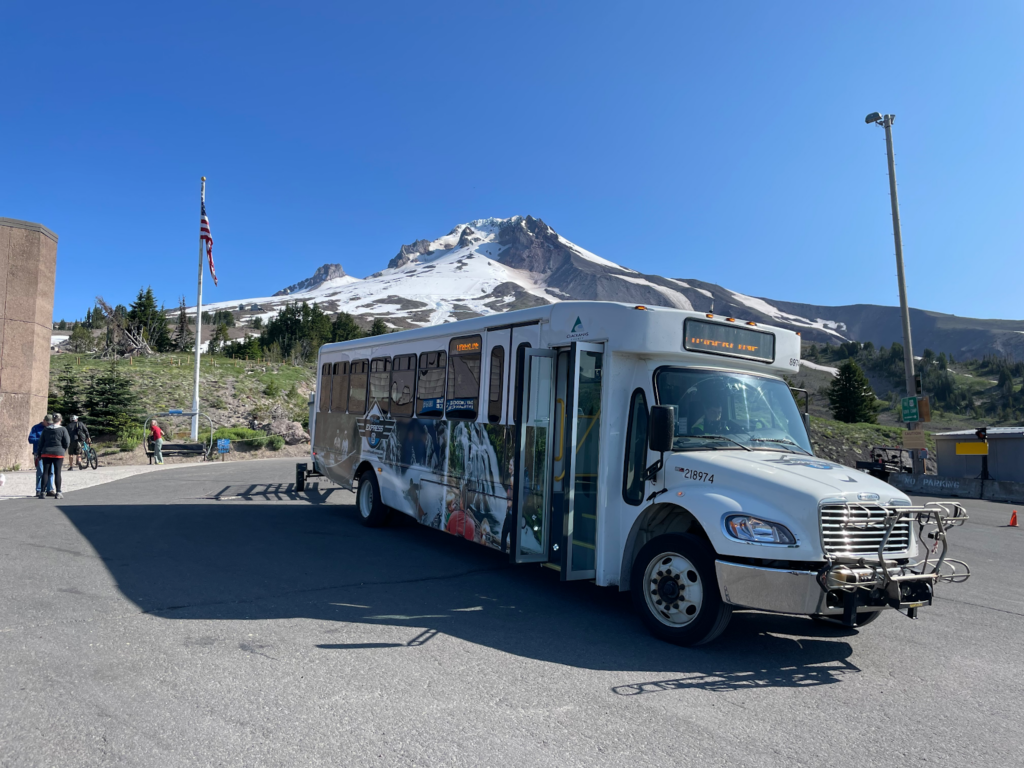 A bus waits to transport passengers to the mountain rising up in the background