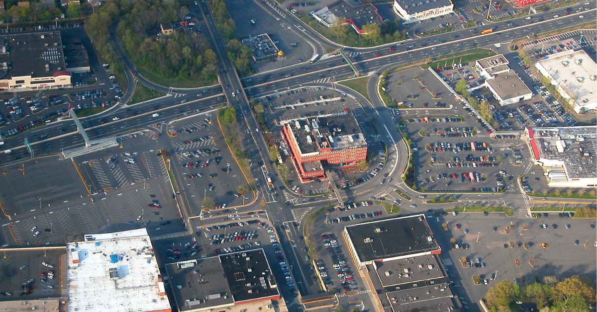 A sea of gray, mostly empty parking spots surround a single building