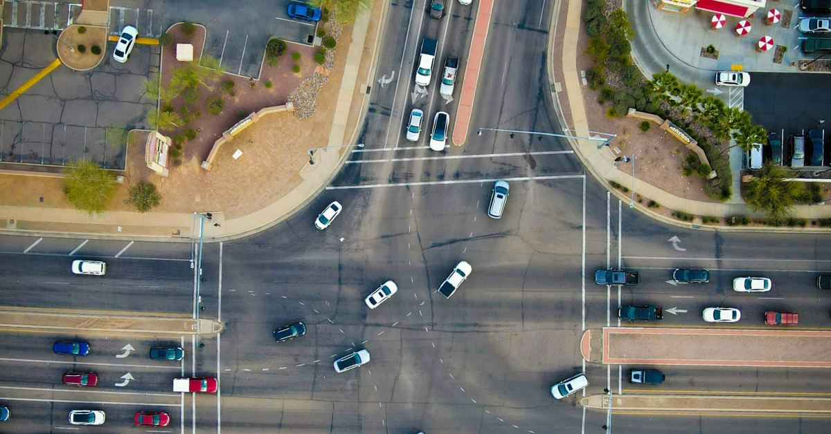 Cars travel quickly down a multi-lane intersection surrounded by multiple parking lots