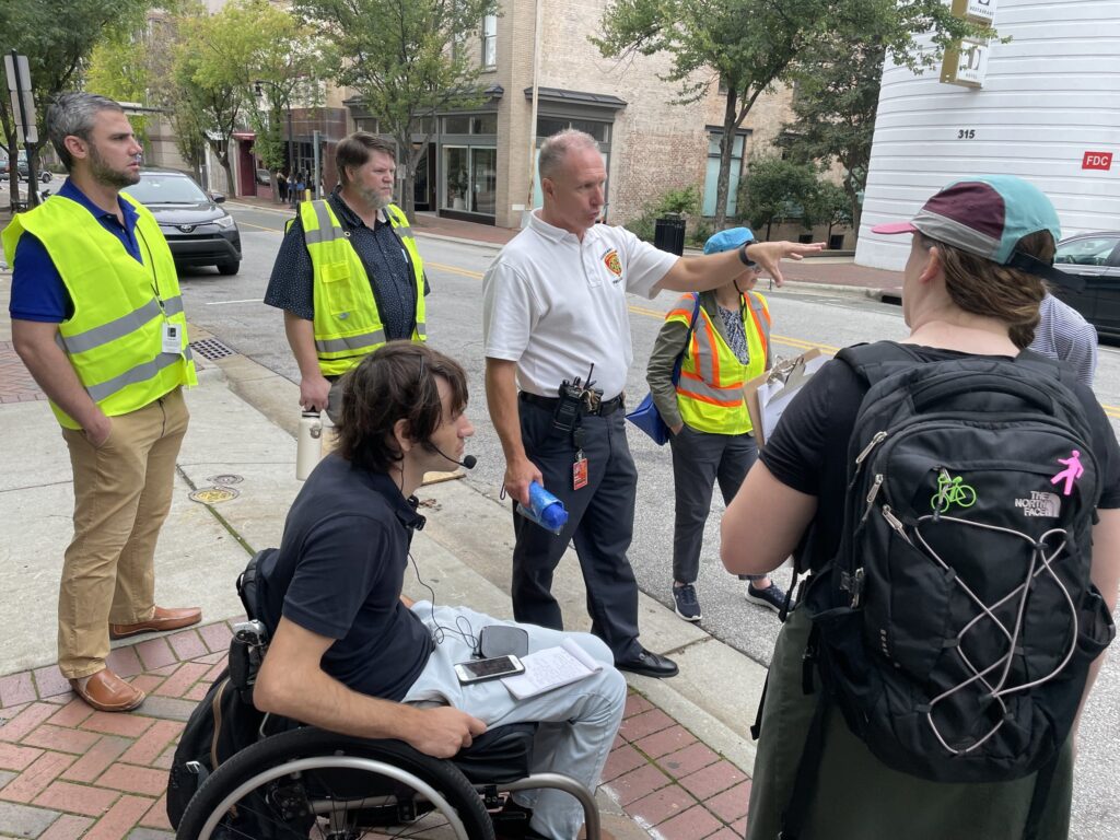 SGA employee Dustin Robertson speaks into a microphone during the walk audit in downtown Durham