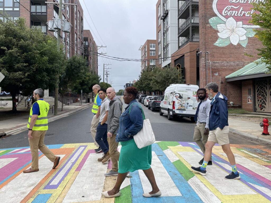 Walk audit participants walk across a brightly painted crosswalk in downtown Durham