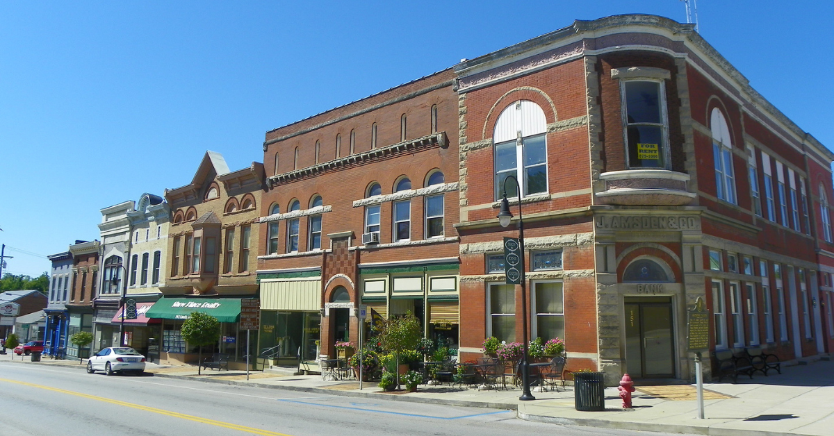 A street in downtown Versailles is lined by historic brick buildings, flower pots, and street lamps