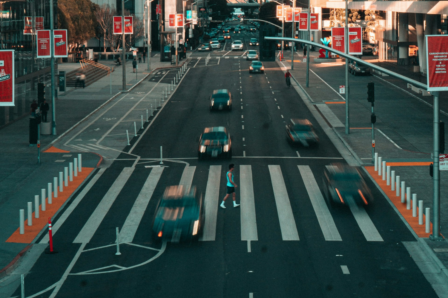 Cars drive straight through a crosswalk while a pedestrian attempts to cross